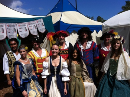 Crew of Art Institute students working at the Renaissance Festival posing with a group of performers.